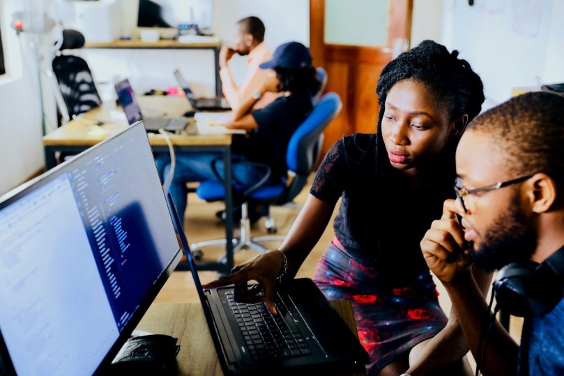 Woman and man sitting in front of a monitor looking at learning analytics